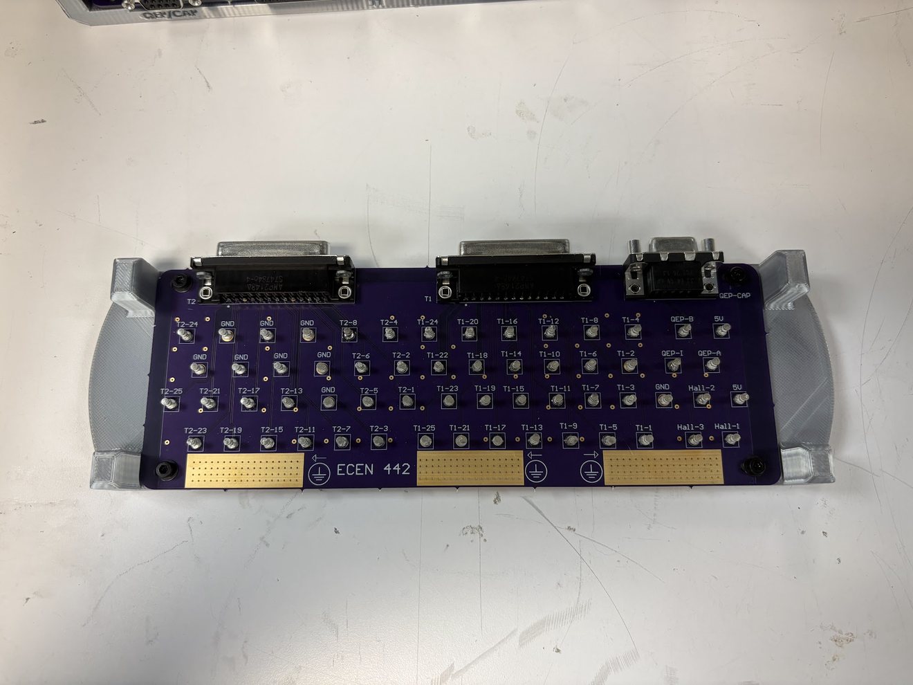 A finished board in its printed holder, with the DB connectors along the top and labelled test points for each lab signal.